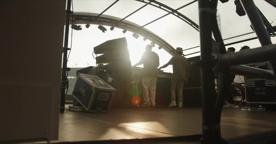 Musicians are on a stage playing music as the sun shines brightly upon them
