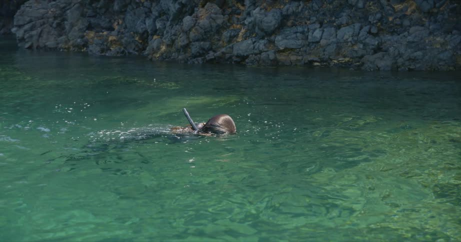 A woman lowers herself into the water to snorkel