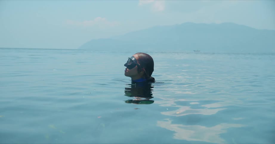 A person is wearing swimming goggles and their head is sticking out of the water