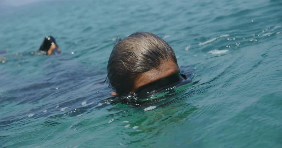 A person swimming with goggles and flippers in water