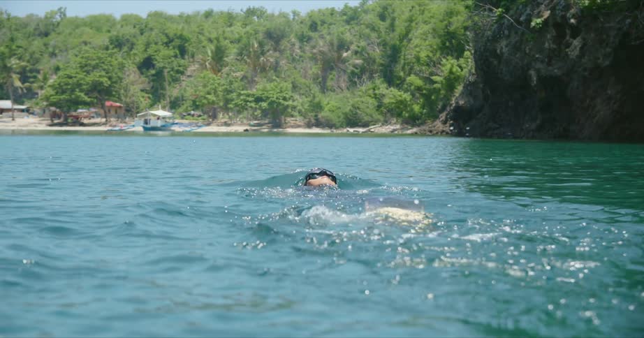 A woman swims on her back on the surface of the ocean