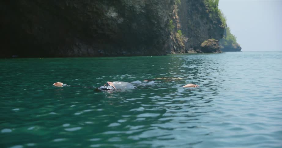 A person is floating in the water by the shore