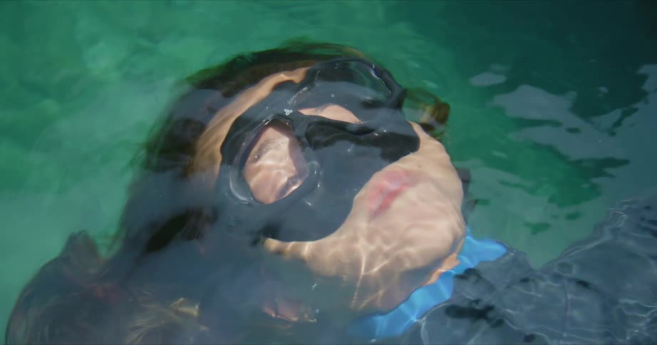 A diver relaxes on her back just under the surface of the ocean