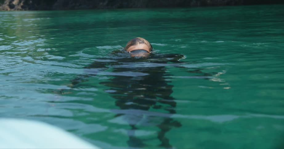 A woman dives below the shore water