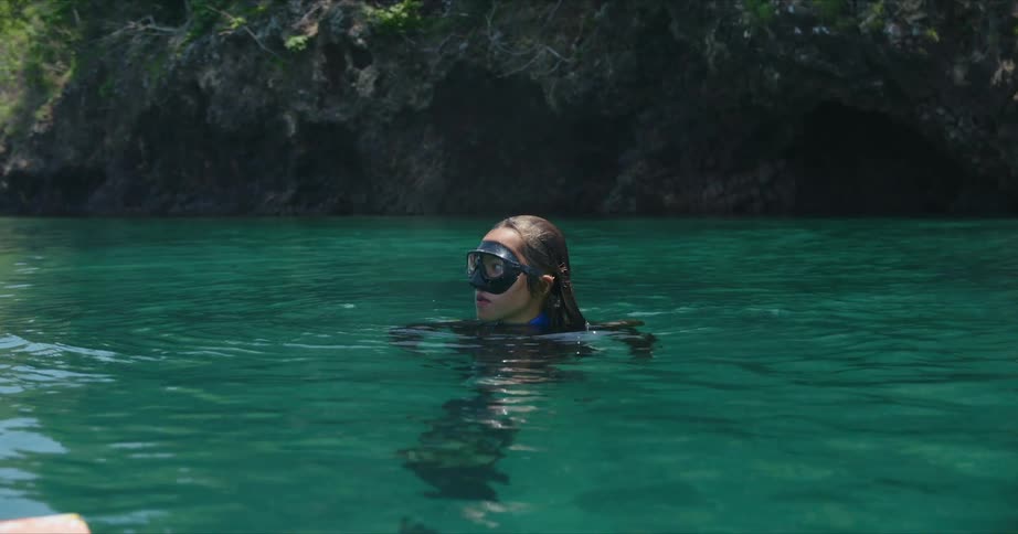 A woman in scuba gear with her head out of the water