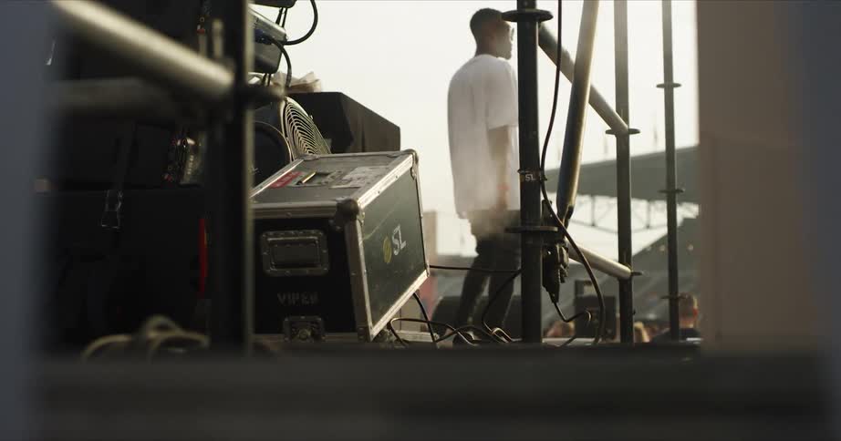 A musician dances on stage in an outdoor stadium during rehearsal