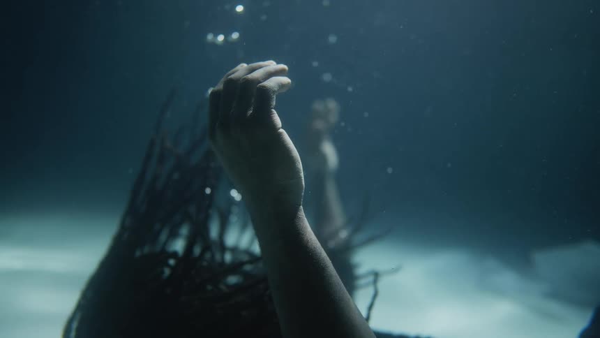 A man falls in the water with his hands up and eyes closed