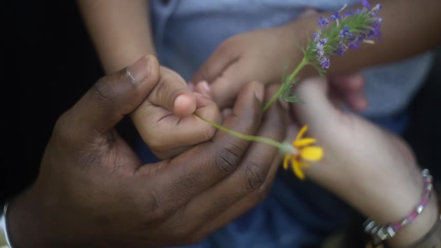 Two people holding hands while holding flowers