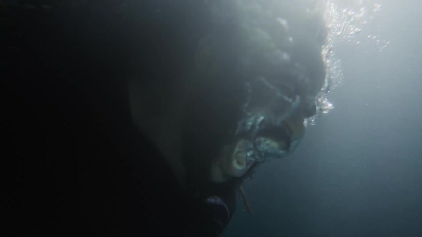 Man with beard an braided hair screams underwater