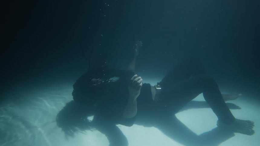 A man laying down underwater with bubbles