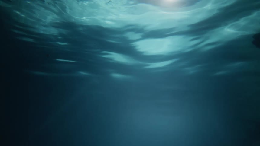 View from underwater as water ripples and light can be seen from above