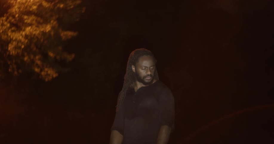 A man standing outside with a tree in the background