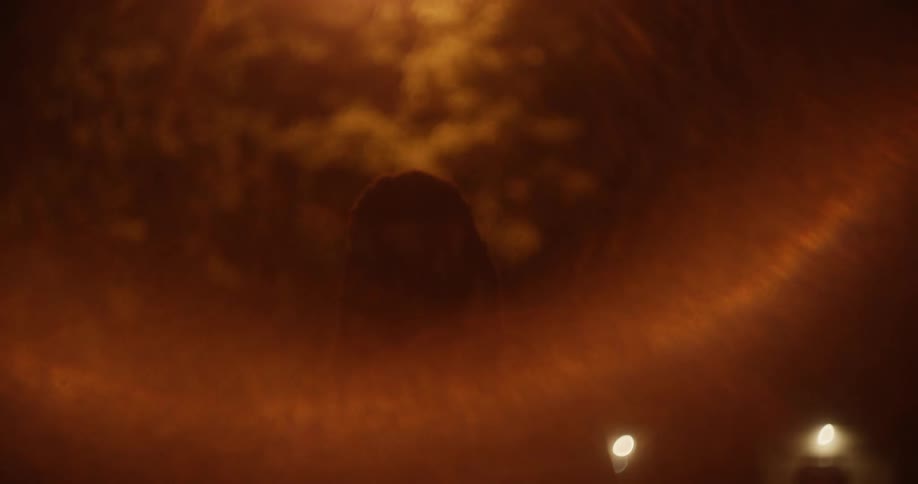 A man standing in a street with a light flashing on his face with trees in the background
