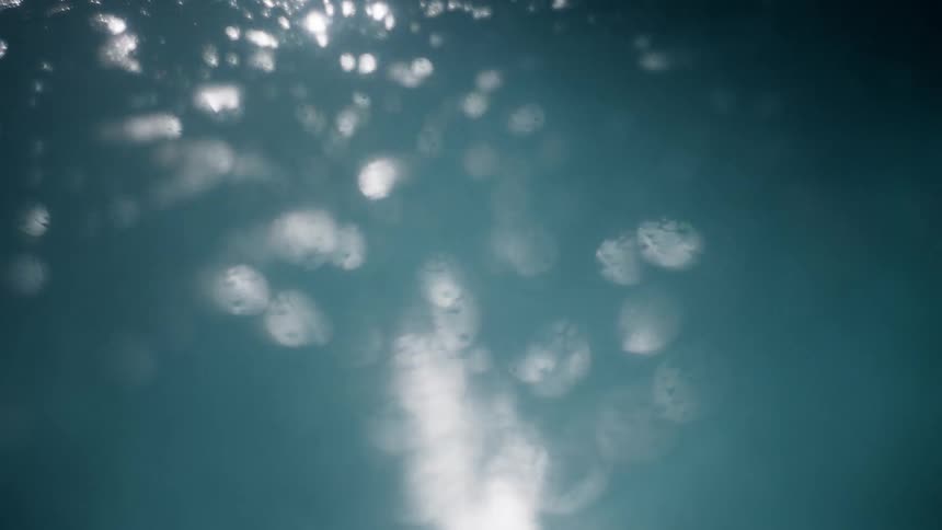 Ocean surface bobs up and down reflecting bright sunlight