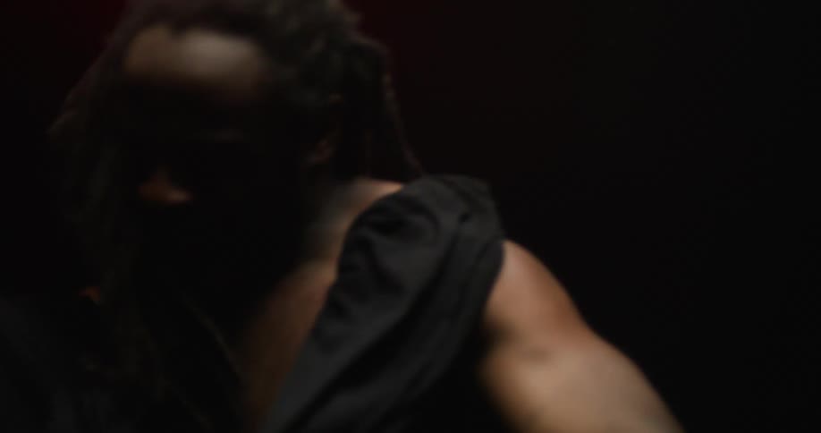 A man tears his shirt off and throws it in the dark