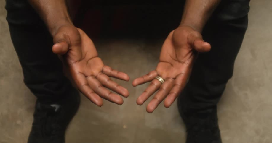 Man with black shoes and pants looks down at his hands