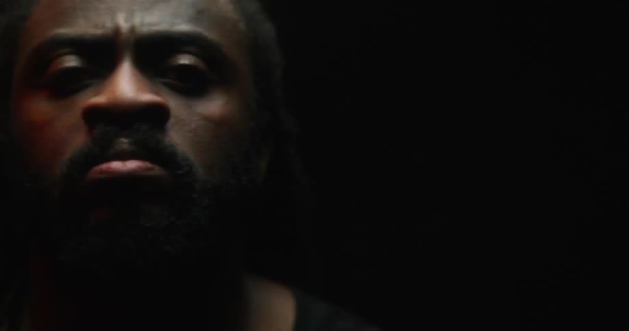 Strobe lights are flashing on the face of a black man and colored lights in the background are changing