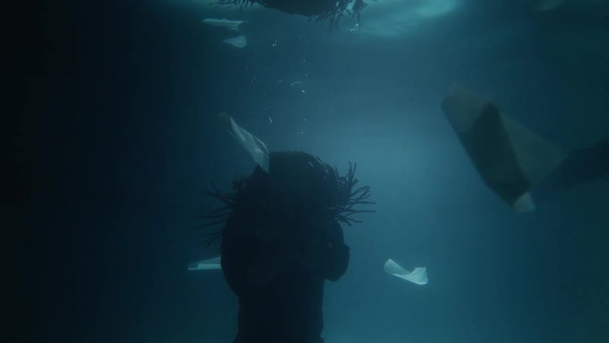 An abstract visual where a man with braids in silhouette is floating underwater with abstract rocks floating under the water