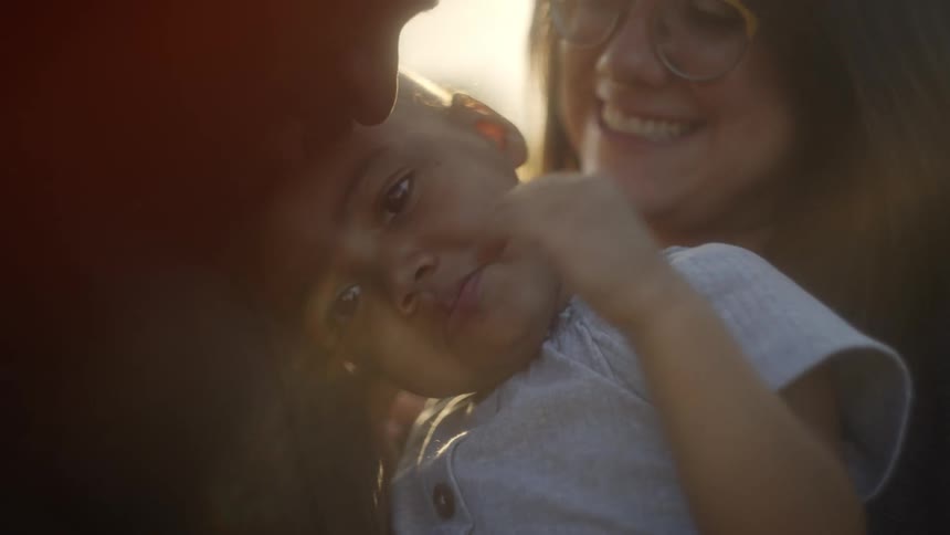A mom cuddles in close behind her daughter held by dad