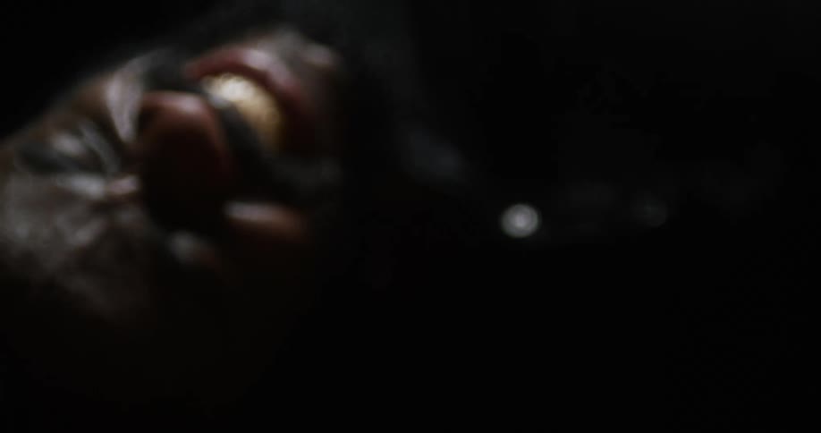 Man with beard and braided hair clenches his fist and writhes around on the ground