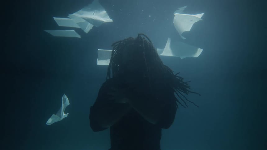 A man is floating underwater with papers around him