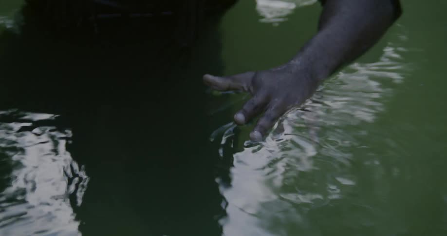 A person with a ring standing in water with reflections