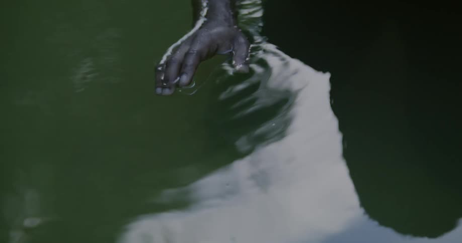 A man is in some water and moves his hands across the top