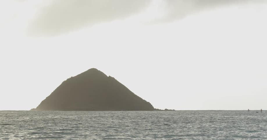 A large rock is jutting out of the water in the distance