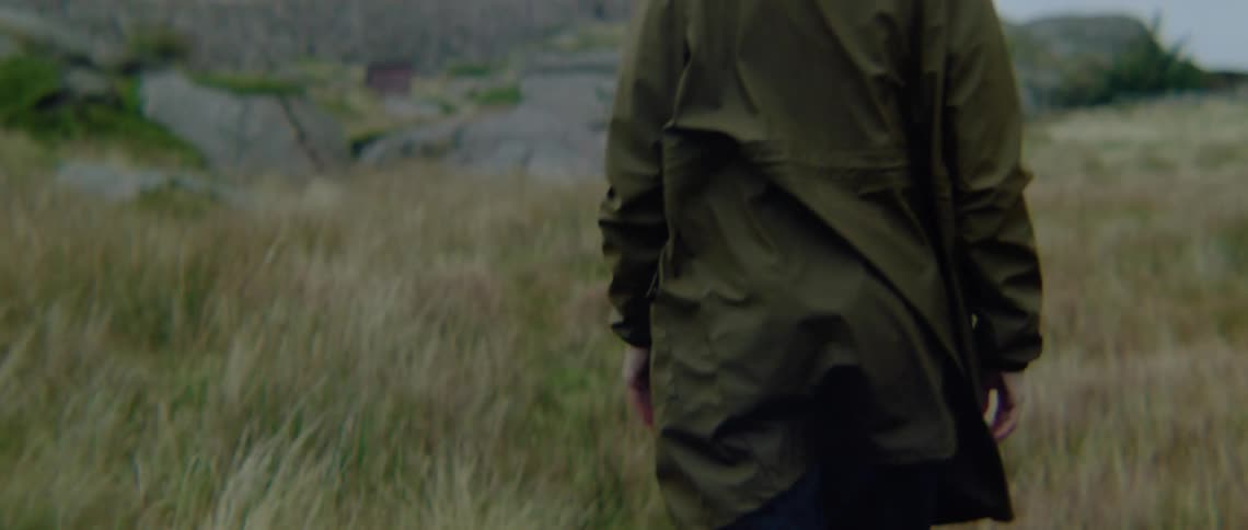A woman walks toward a wall of rocks in a field