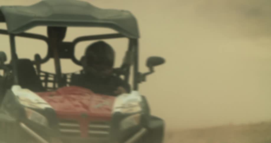 Dune buggy drivers come around in a curve on a dirt race track