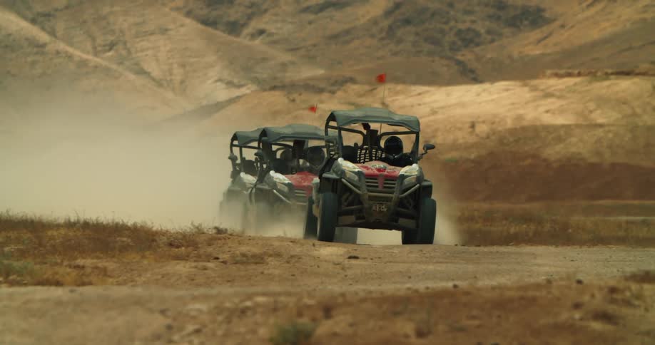 Three off road vehicles race near the hills