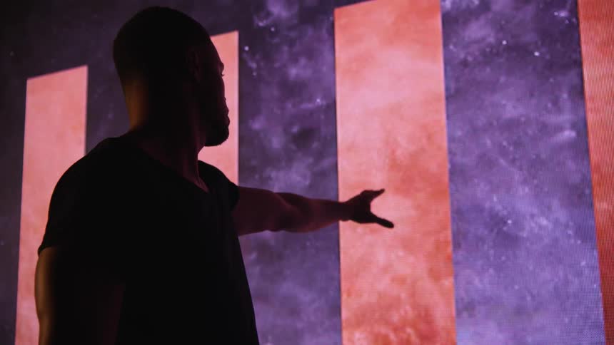 A man is standing still and reaching for a smoky screen