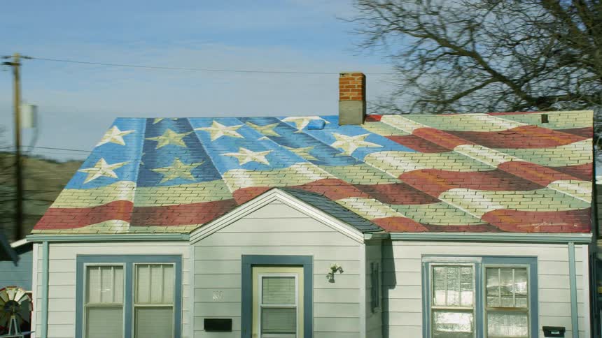 A house in a neighborhood has an american flag painted on the roof