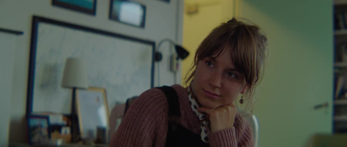 A woman in a room with a lamp a wall and a doorway in the background