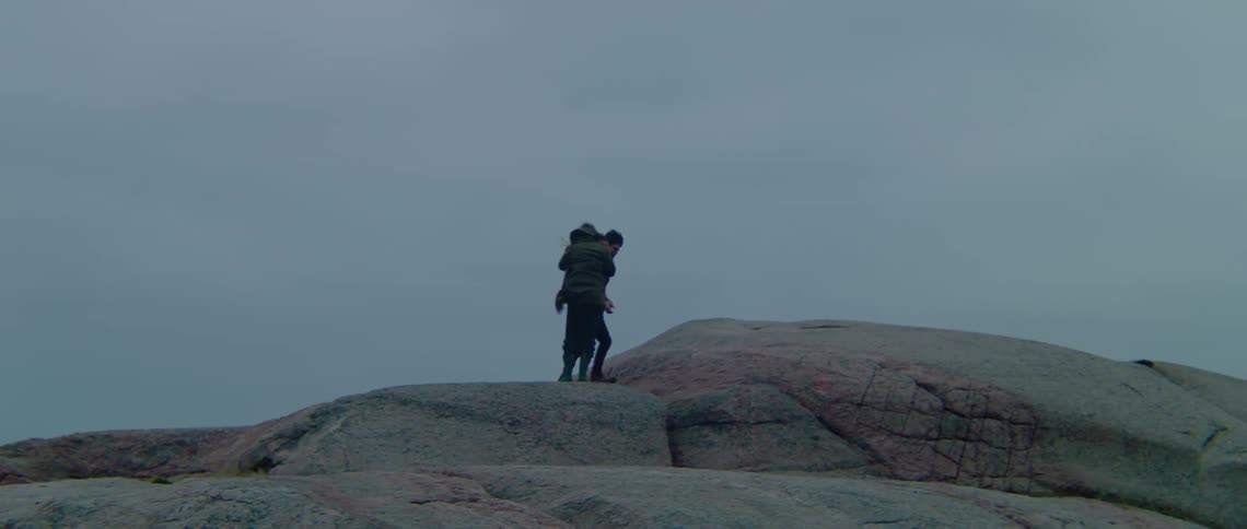 Two people are climbing up a rocky mountain top