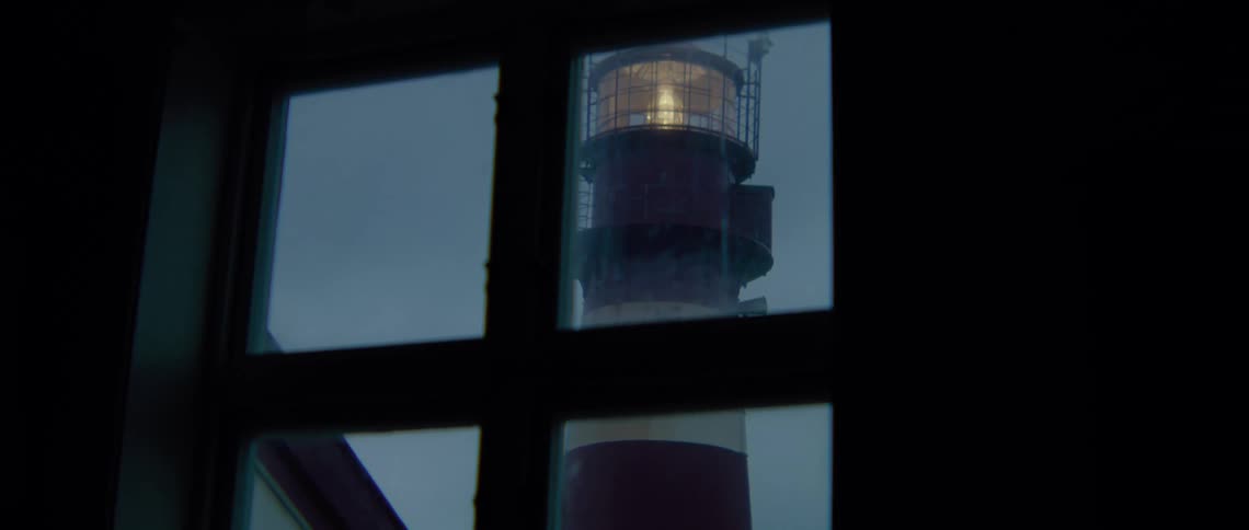 A lighthouse seen though a window with the light on