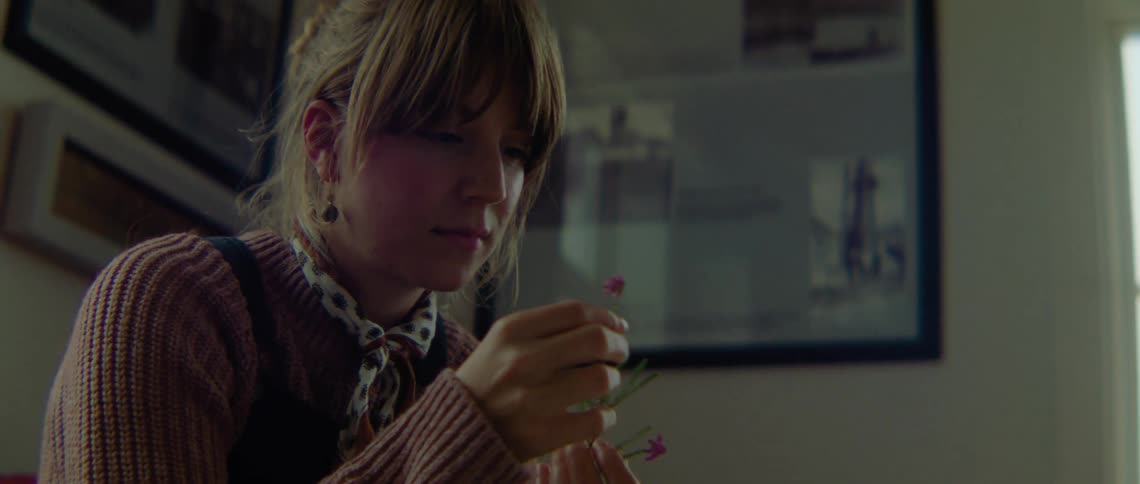 A woman is sitting down and arranging small pink flowers