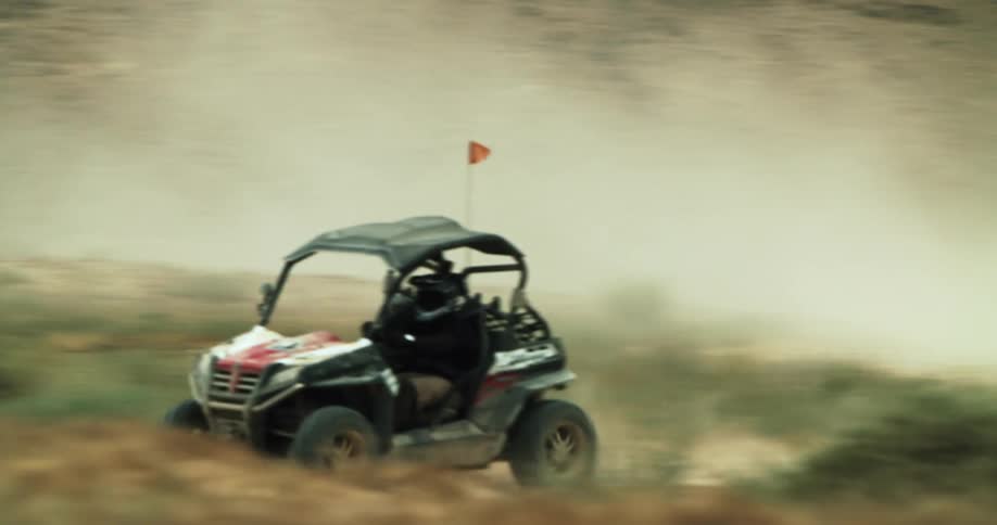 People with helmets racing buggies