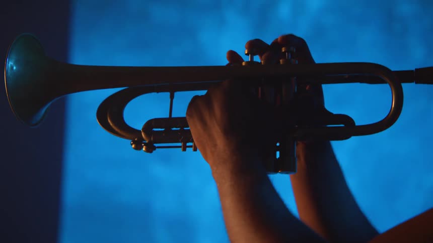 A man is playing a trumpet indoors at night