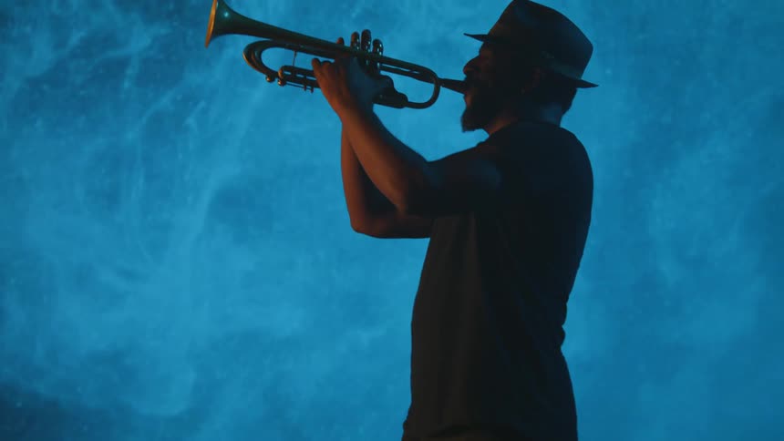 Man playing trumpet in front of a blue screen
