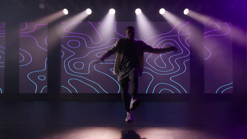 A man in a room dancing with a wall and a screen in the background