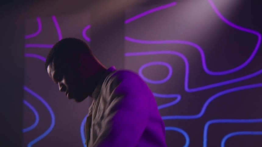 A man in a room dancing with a wall and a screen in the background