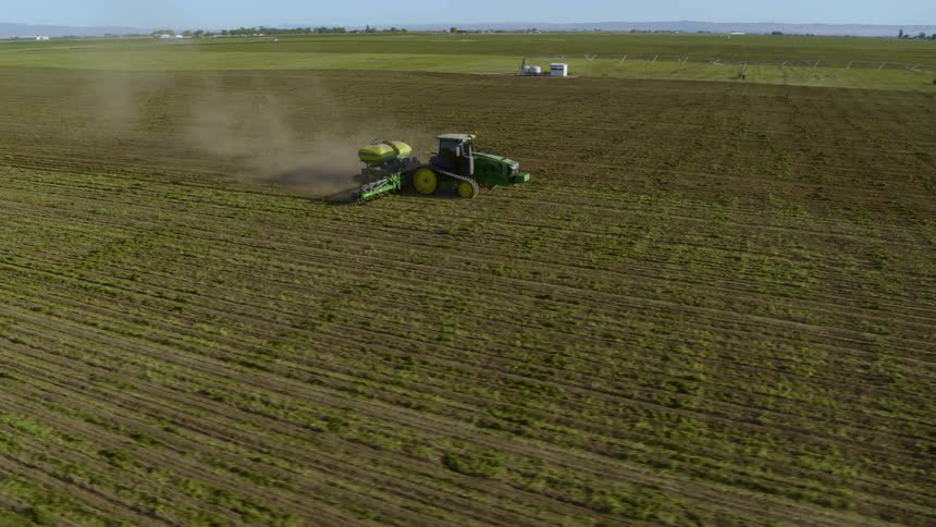 Orbit around a large tractor working on fertile farmland