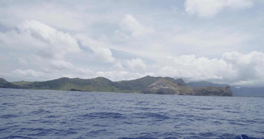 An ocean and mountains on a cloudy day
