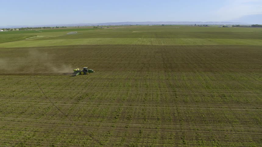 Wide orbit around a tractor planting sweet corn on a large farm field