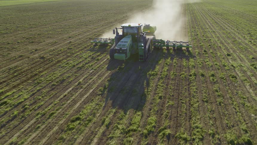 Dynamic orbit in front of a backlit tractor pulling a high speed planter