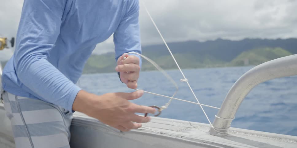 A person ties a knot around a metal loop on a boat