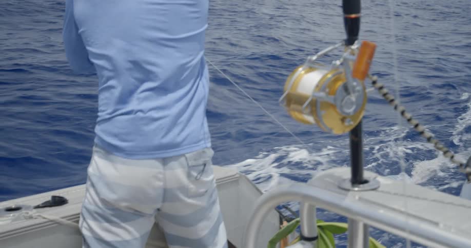 A man is pulling his fishing line in on a boat