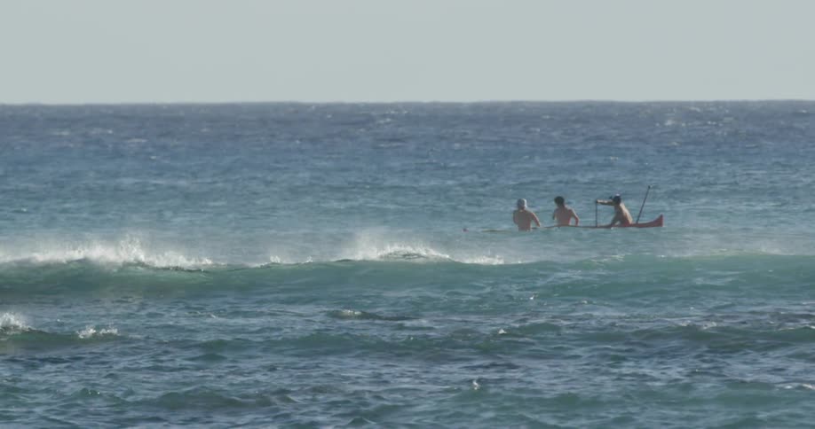People riding a canoe over ocean waves
