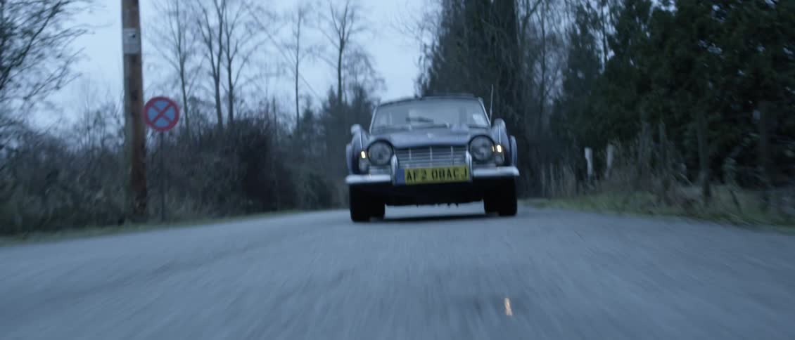A man drives a vintage car down a rural highway